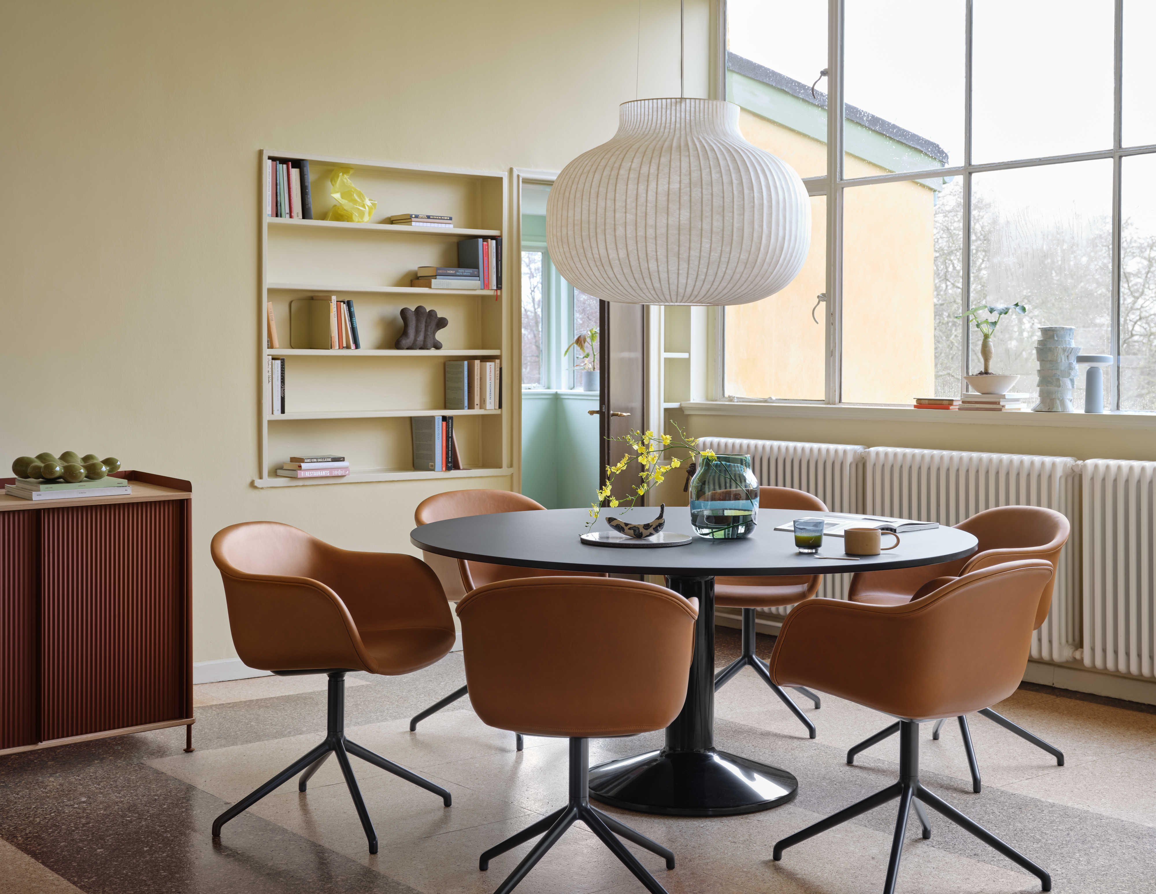 Midst Table Ø160 cm in Black - Fiber Armchair Swivel Base in Refine Leather Cognac/Black - Strand Pendant Lamp Ø60 cm in White - Silent Vase Ø20 cm in Dark Green - Enfold Sideboard 100x45 H85 cm in Deep Red - Ease Portable Lamp in Light Blue 
