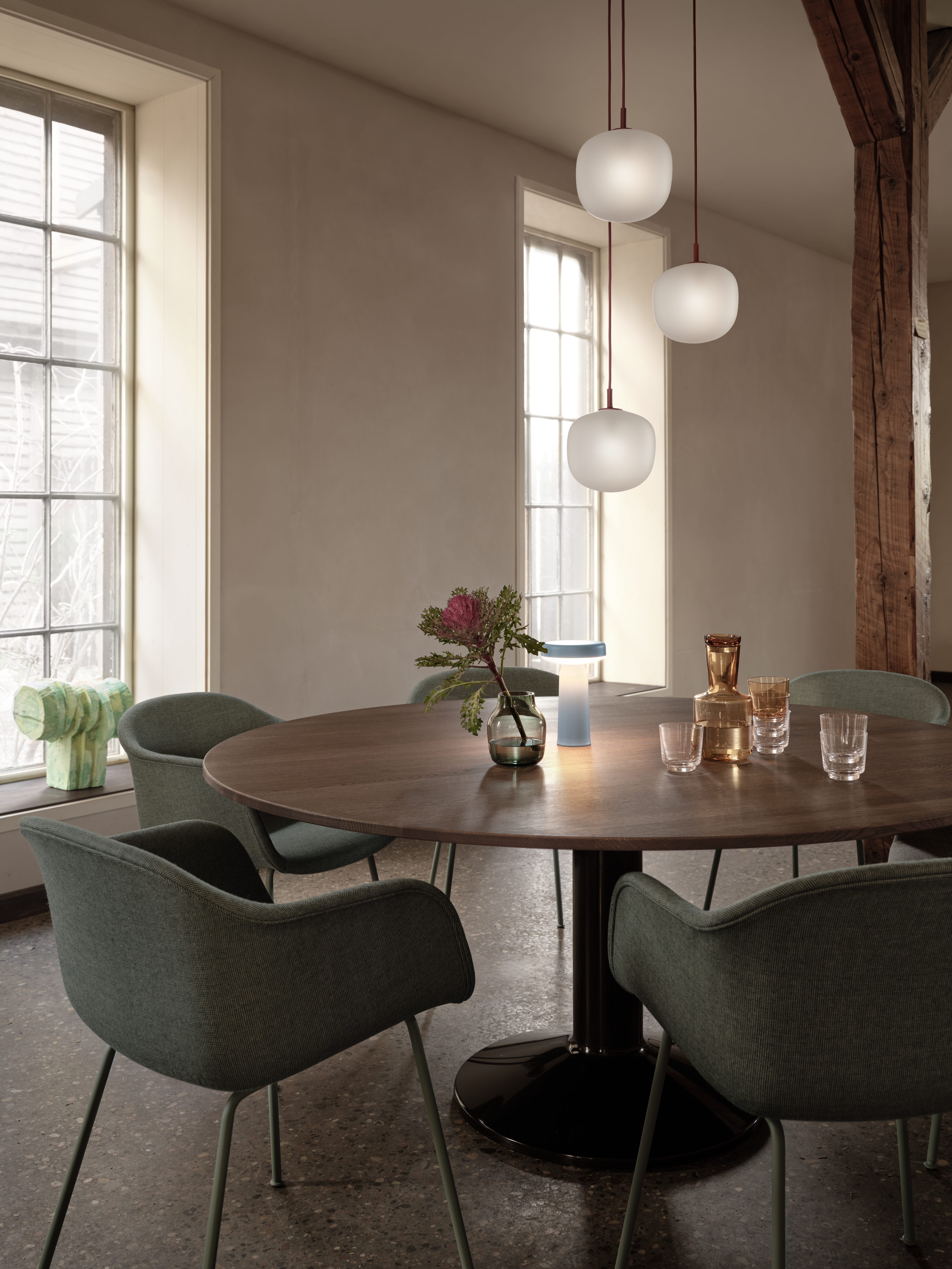 Midst Table Ø160 cm in Dark Oiled Oak/Black - Fiber Armchair Tube Base Sabi 921/Dusty Green - Rime Pendant Lamp Ø18 cm in Deep Red - Ease Portable Lamp in Light Blue - Silent Vase Ø11 cm in Dark Green - Raise Carafe in Burnt Orange - Raise Glasses in Clear