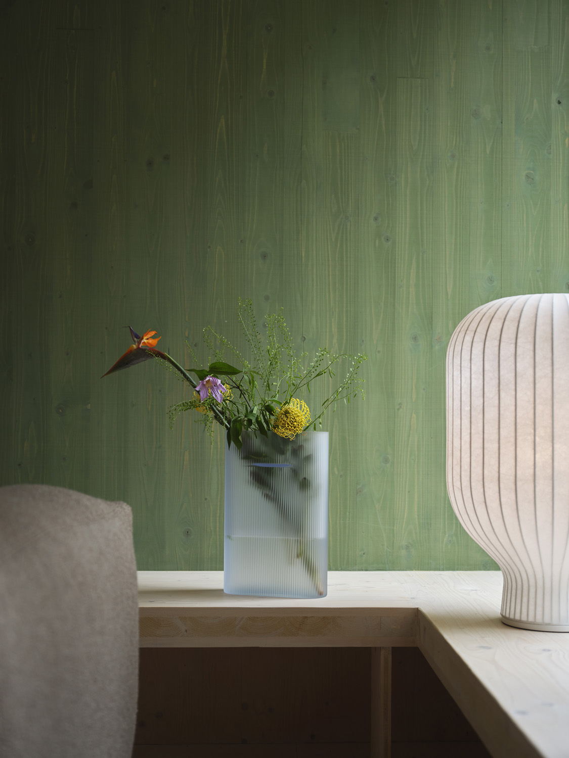 The sculptural form with soft curves enhances the feeling of soft, inviting light. The Strand Table Lamp in size H59 sits perfectly between a floor and table lamp, ensuring versatile use across various settings. Here, it is elegantly styled with a light blue Ridge Vase, adding an artistic touch to the decor.