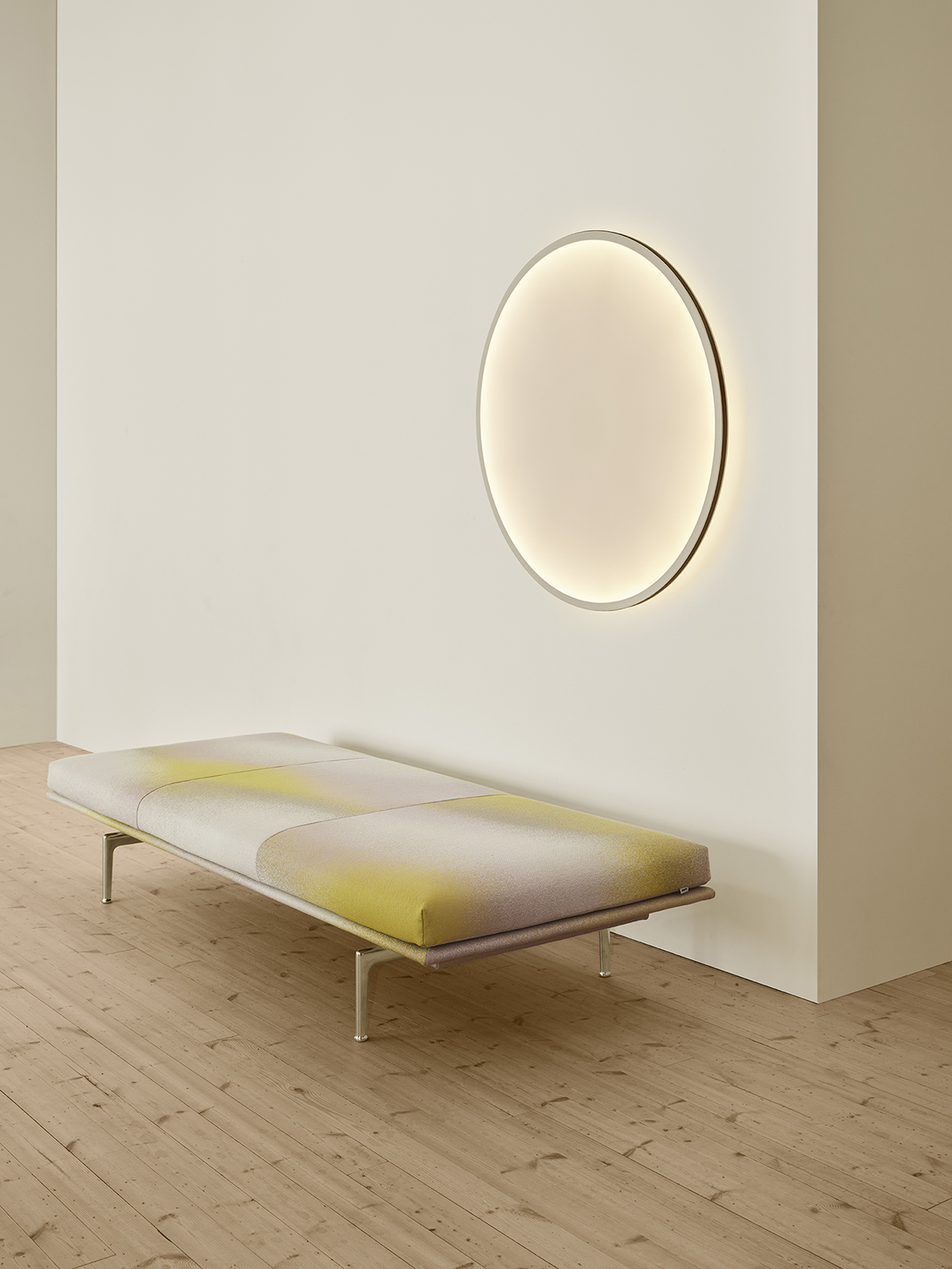 Calm Wall/Ceiling Lamp casting a soft halo of light above a modern, minimalistic daybed.