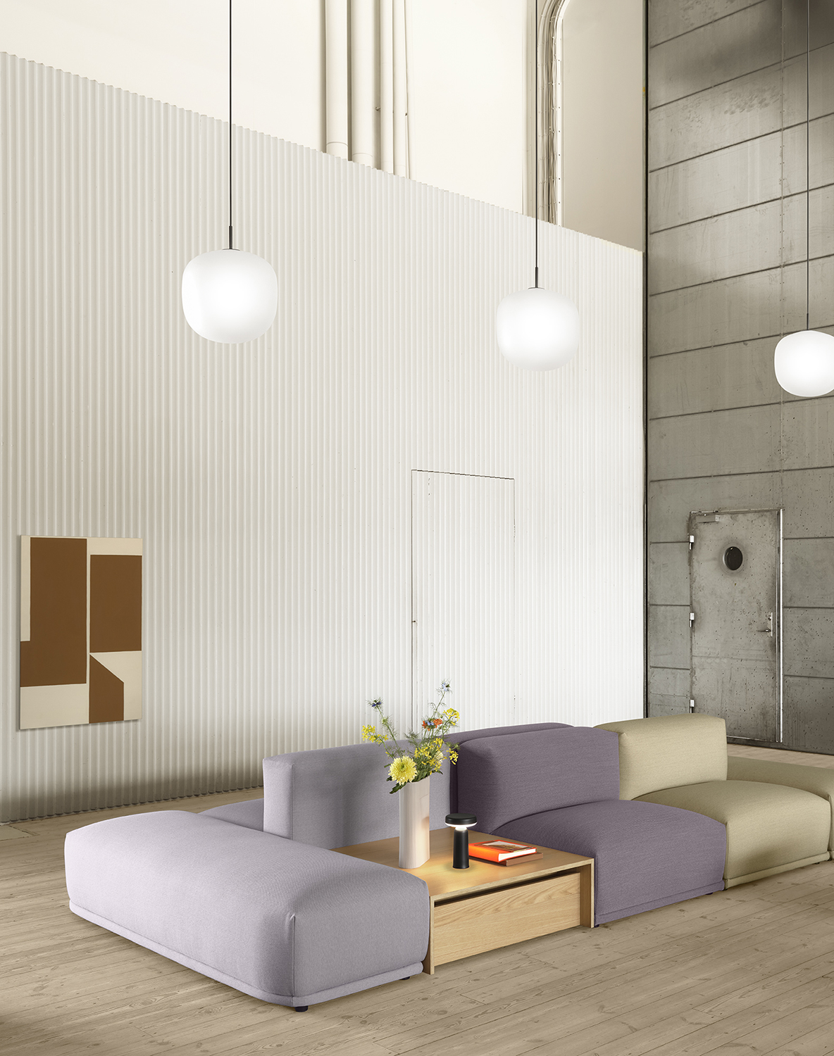 Connect Sofa in a spacious, minimalistic room with white and grey walls, accented by three glass pendant lights hanging above.
