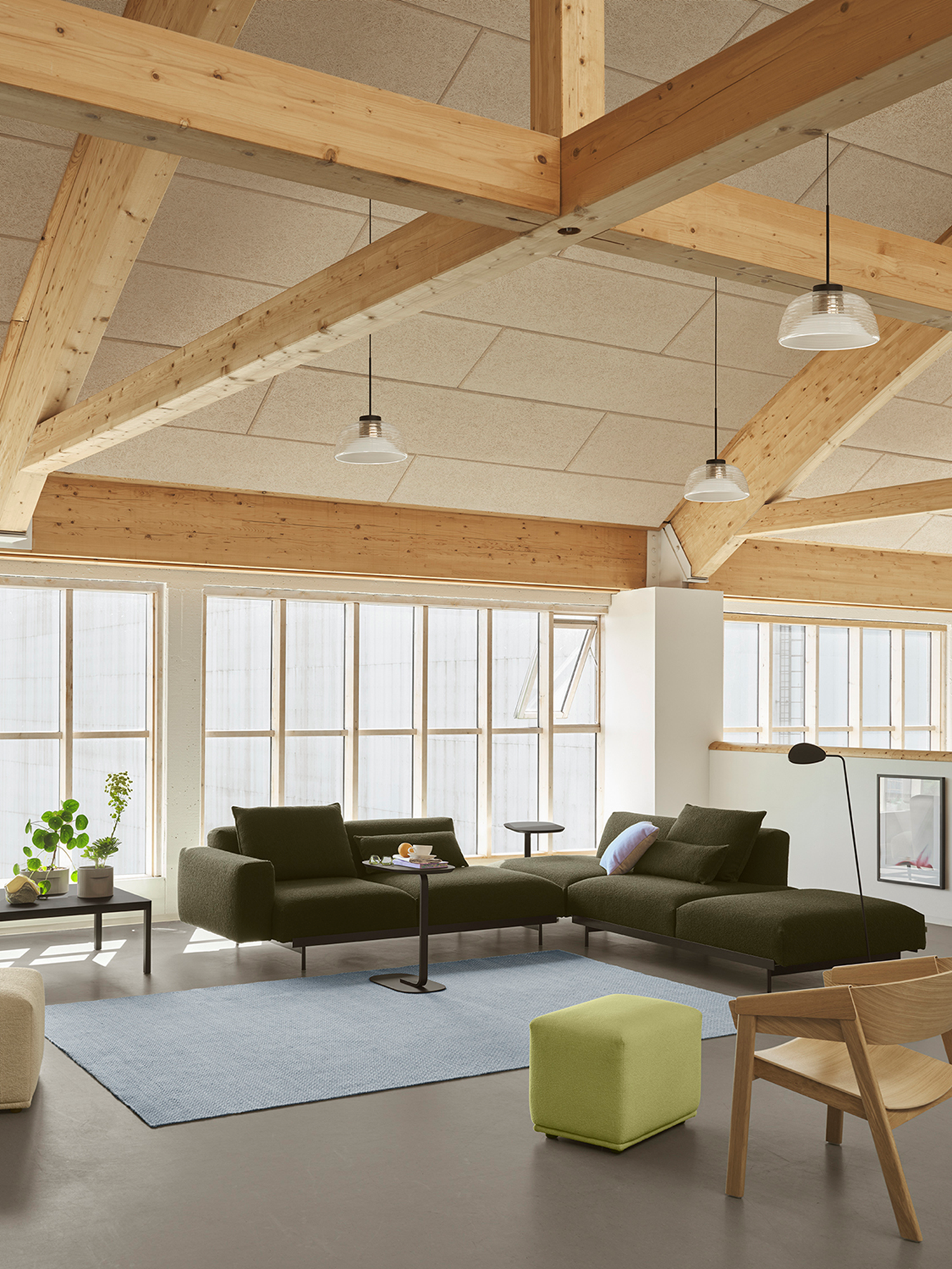 In Situ Sofa in a dark tone placed in a modern room, complemented by a light blue rug and glass pendant lamps for a stylish, contemporary atmosphere.