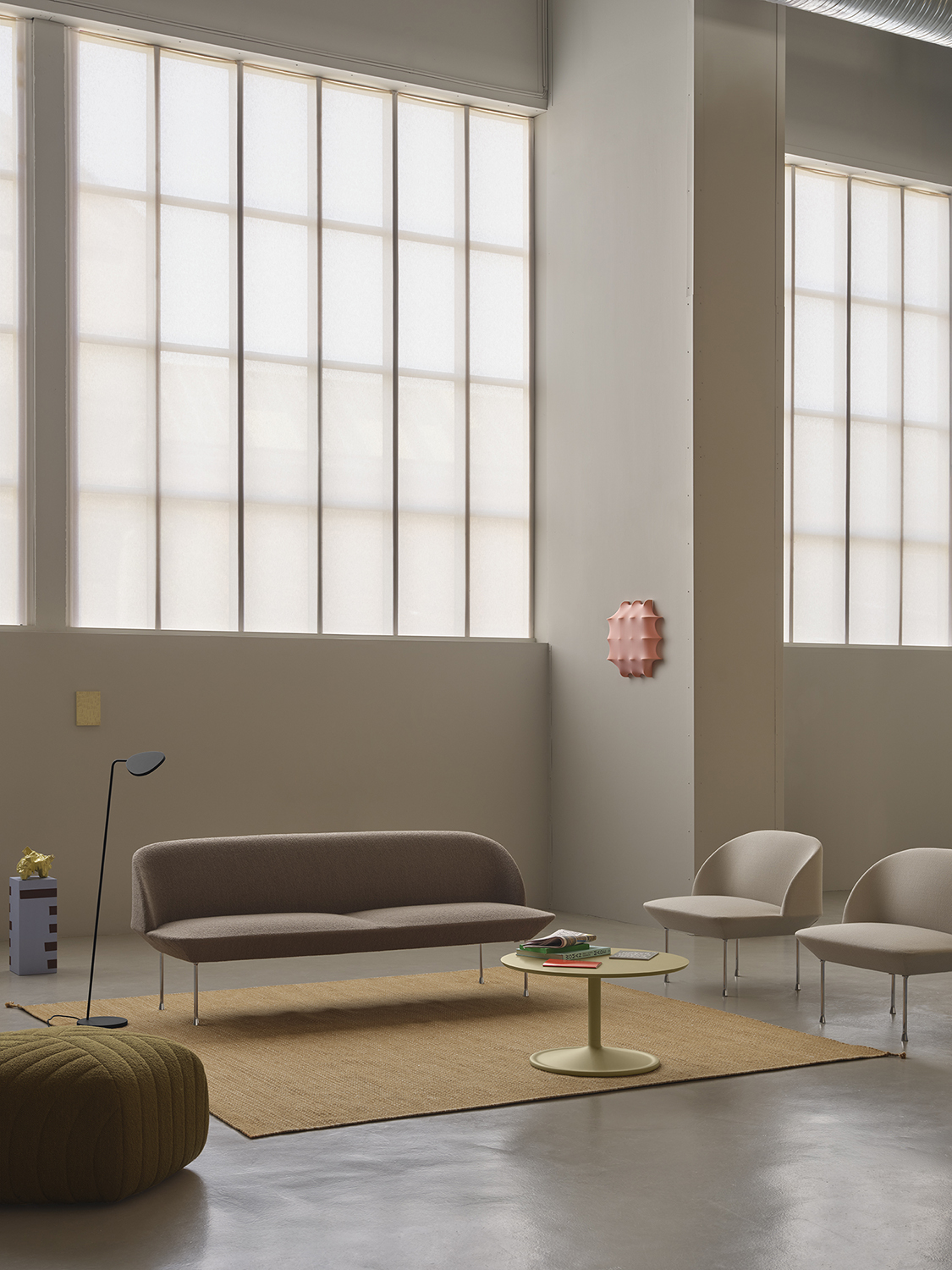 Oslo 3-seater sofa in light brown-grey, positioned next to a simple, minimalistic black floor lamp and two light grey lounge chairs.