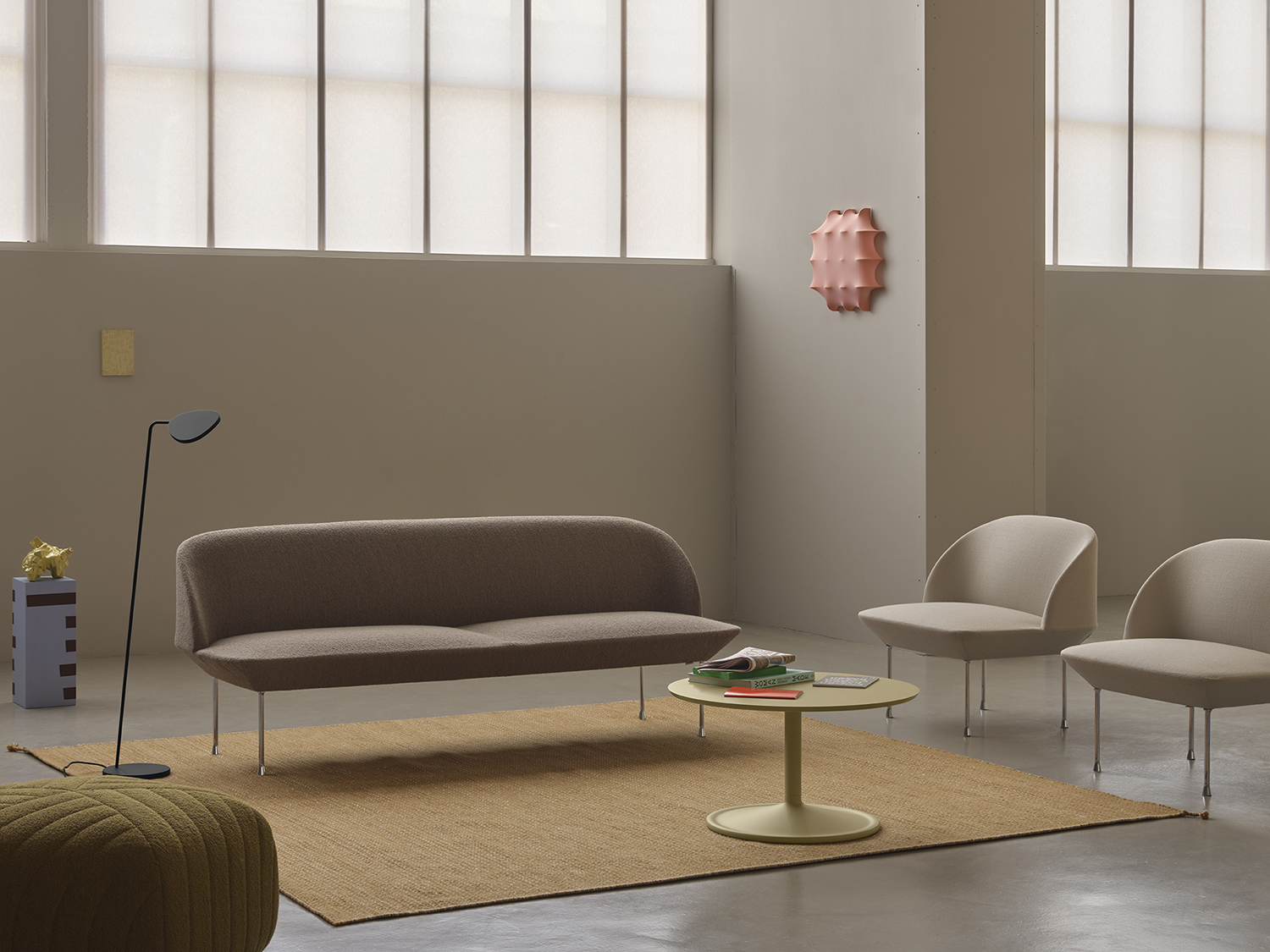Oslo 3-seater sofa in light brown-grey, flanked by two light grey lounge chairs and a minimalistic black floor lamp. A simple round coffee table sits at the center of the room.